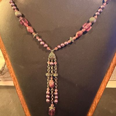 mauve and purple beaded type statement necklace featuring an ornate filigree drop tassel