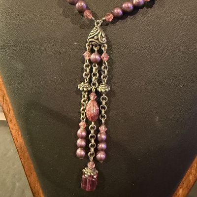 mauve and purple beaded type statement necklace featuring an ornate filigree drop tassel