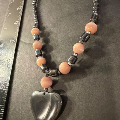Vintage beaded necklace featuring metallic gray hematite beads and peach cat's-eye glass beads accented with a heart-shaped pendant.