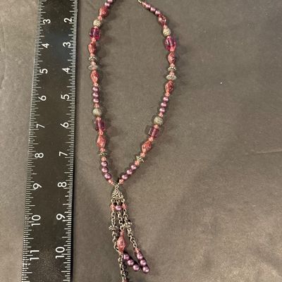 mauve and purple beaded type statement necklace featuring an ornate filigree drop tassel