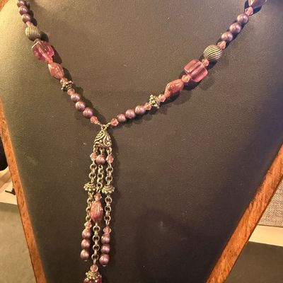 mauve and purple beaded type statement necklace featuring an ornate filigree drop tassel