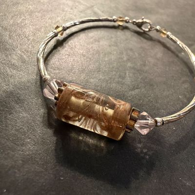 artisan silver-tone wire bracelet featuring a prominent cylindrical champagne and amber foil glass focal bead flanked by pale pink bicone...
