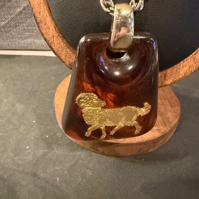 vintage 1970s Helena Rubinstein Aries zodiac pendant necklace featuring a brown tortoise lucite body with an inlaid gold-tone ram symbol