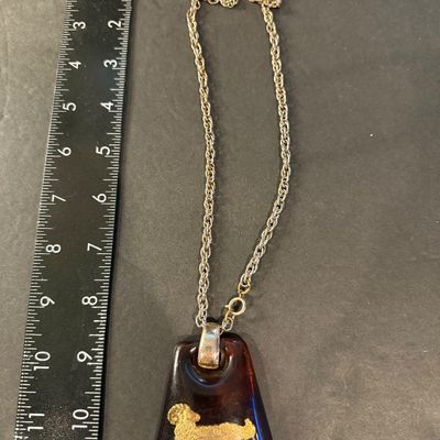 vintage 1970s Helena Rubinstein Aries zodiac pendant necklace featuring a brown tortoise lucite body with an inlaid gold-tone ram symbol