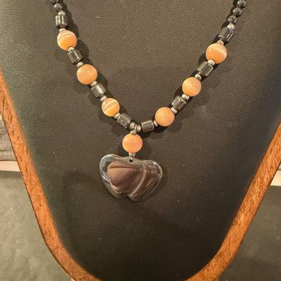 Vintage beaded necklace featuring metallic gray hematite beads and peach cat's-eye glass beads accented with a heart-shaped pendant.