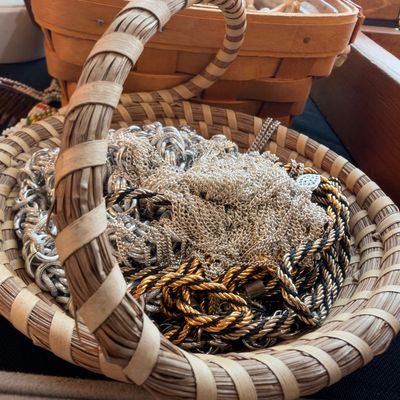 Silver and gold tone chain necklaces in coiled woven basket