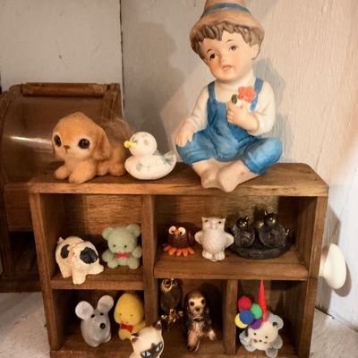 Porcelain boy figurine, miniature animals on wood shelf