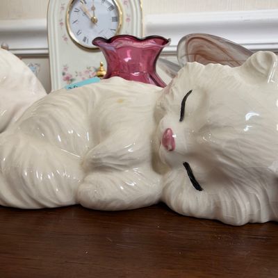 Sleeping white ceramic cat and cranberry glass vase