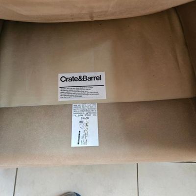 Crate & Barrel manufacturer label and care tag on the underside of a tan upholstered furniture piece.