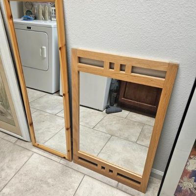 Two wood-framed wall mirrors, including a tall pine-framed full-length mirror and a Mission-style oak mirror with decorative cutouts.