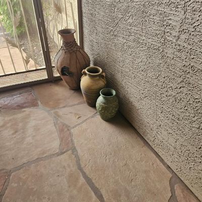 Trio of rustic ceramic floor vases in varying sizes and earthy tones, including a large brown vessel with decorative netting, a...