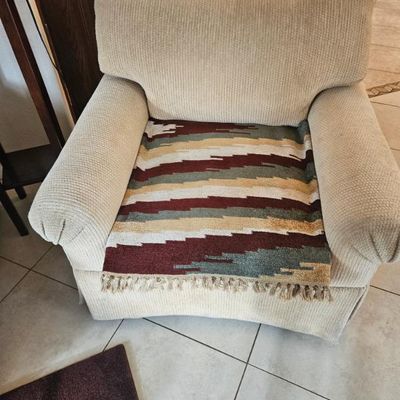 Beige corduroy upholstered armchair featuring a Southwestern-style woven throw blanket draped over the seat cushion.