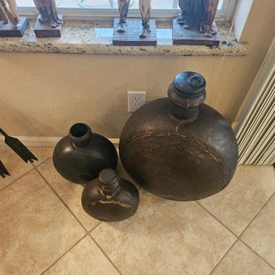 Trio of rustic, dark-finished canteen-style decorative vessels in varying sizes