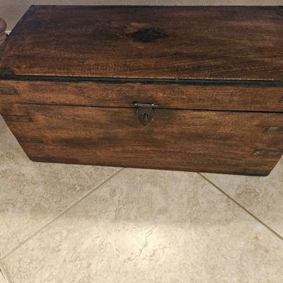 Vintage dark wood storage chest featuring metal corner brackets, a central latch, and a decorative diamond inlay on the lid.