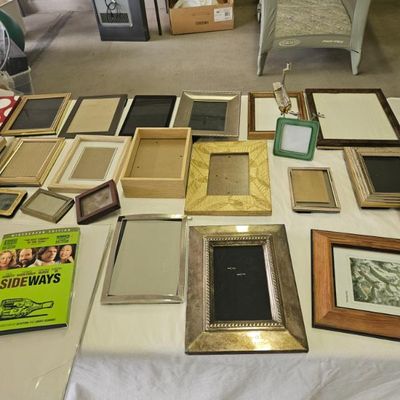 Assortment of picture frames in various sizes, styles, and finishes, including wood, metal, and plastic.