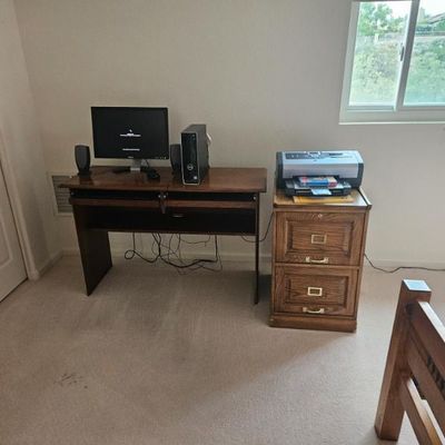 Dell computer on a wooden computer desk with a pull-out keyboard tray, paired with a matching two-drawer oak filing cabinet holding a...