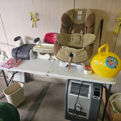 Assorted baby and toddler items, including a Brita car seat, a booster seat, a yellow hopper ball, and a portable space heater