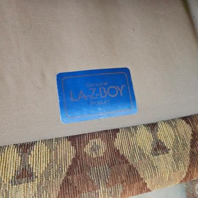 Genuine La-Z-Boy product label on the underside of an upholstered armchair with a patterned tapestry fabric.