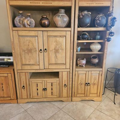 Two-piece Southwestern-style oak wall unit featuring carved geometric details, open shelving, and lower cabinet storage, styled with...