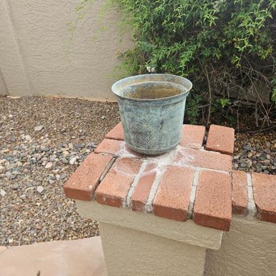 Weathered metal planter with a verdigris patina and embossed leaf design
