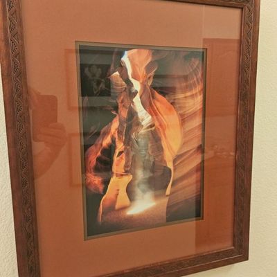 Framed photograph of Antelope Canyon, featuring a carved wooden frame with Southwestern-style geometric patterns and a terracotta-colored...