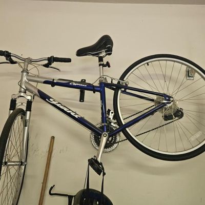 Giant Cypress hybrid bicycle in blue and silver, featuring front suspension and a multi-speed drivetrain, mounted on a wall rack.