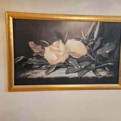 Framed floral print depicting white magnolias on a dark background, set in a wide, textured gold-finished frame.
