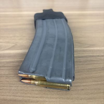 A Thirty Round Curved Metal Magazine Fitted with a Magpul Floor Plate Accessory and Loaded Ammunition