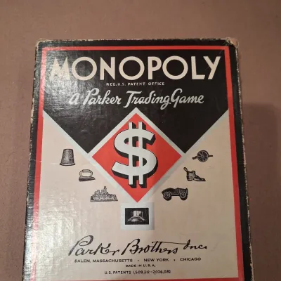 1935 MONOPOLY GAME AND ANTE-UP-RUMMY BOARD WITH MARBLES STORED IN THE FRAME PLUS PLAYING CARDS