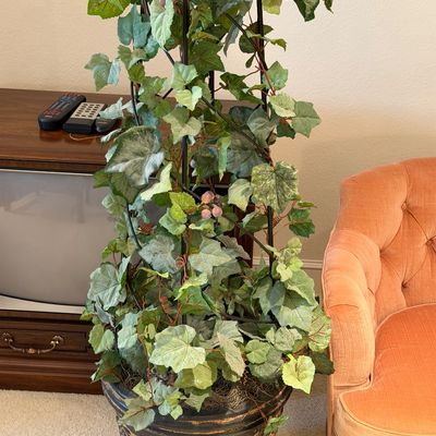 WOODMARK ORIGINALS VINTAGE PEACH VELVET TUFTED BARREL ARMCHAIR ON CASTERS AND ARTIFICIAL PLANT CLIMBING A METAL OBELISK TRELLIS