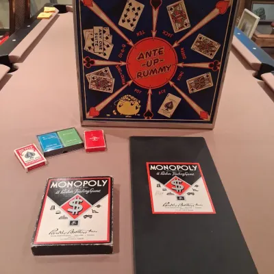 1935 MONOPOLY GAME AND ANTE-UP-RUMMY BOARD WITH MARBLES STORED IN THE FRAME PLUS PLAYING CARDS