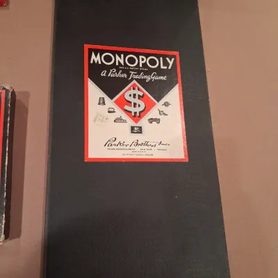 1935 MONOPOLY GAME AND ANTE-UP-RUMMY BOARD WITH MARBLES STORED IN THE FRAME PLUS PLAYING CARDS