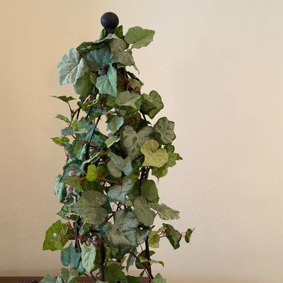 WOODMARK ORIGINALS VINTAGE PEACH VELVET TUFTED BARREL ARMCHAIR ON CASTERS AND ARTIFICIAL PLANT CLIMBING A METAL OBELISK TRELLIS