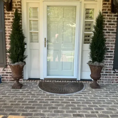 Two Potted Evergreen Topiary Trees with Urn Planters and Doormat