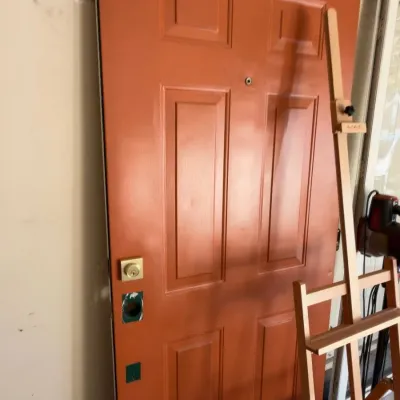 Six-panel exterior entry door, painted terracotta, with hardware
