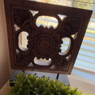 Carved wood medallion panel on stand, boxwood greenery