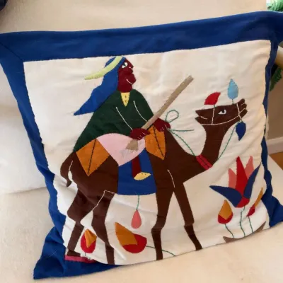 Appliqued camel and rider throw pillow, blue border