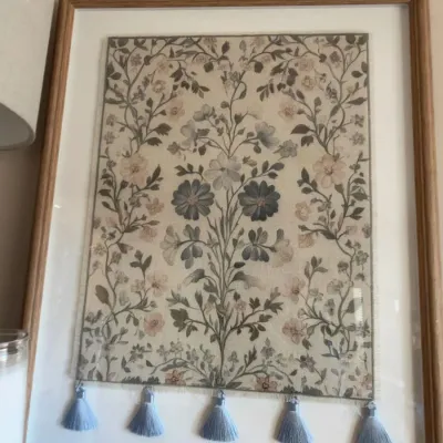 Framed floral needlework textile panel with blue tassels