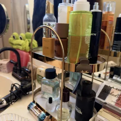 Two-tier gold vanity organizer with fragrances and cosmetics