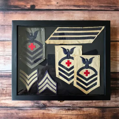 Vintage U.S. Navy rating patches and service stripes presented together in a framed display.