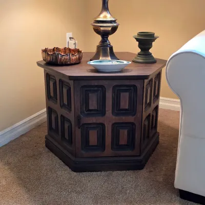 Vintage polygonal wood end table with paneled sides, displayed with a traditional table lamp.
