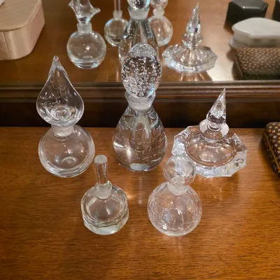 Decorative glass perfume bottles with assorted shapes, faceted details and glass stoppers.