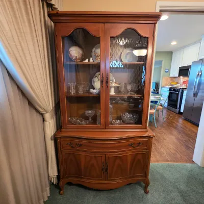 Traditional wood china cabinet with glass-front upper display and enclosed lower storage.