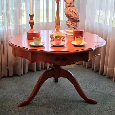Round wood pedestal table with curved legs, decorative table lamp and colorful Danish cups and saucers.