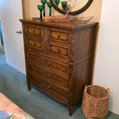 Vintage tall wood chest of drawers with decorative drawer fronts and traditional metal pulls.