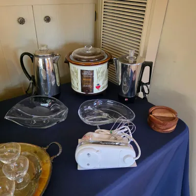 Vintage kitchen appliances and serving pieces, including a slow cooker, electric coffee pot and hand mixer.