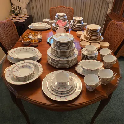 Noritake Rosalie 3052 china with pink rosebuds and gold trim, including plates, cups, saucers and serving pieces.