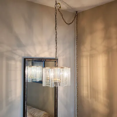 Vintage hanging light with textured glass panels, displayed beside a tall decorative wall mirror