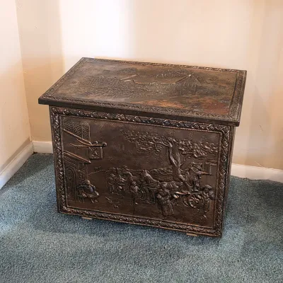Brass repoussé coal box with decorative raised scenes and hinged lid — vintage fireplace accessory.