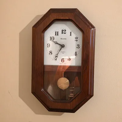 Bulova quartz pendulum wall clock with wood case and easy-to-read Arabic numerals.